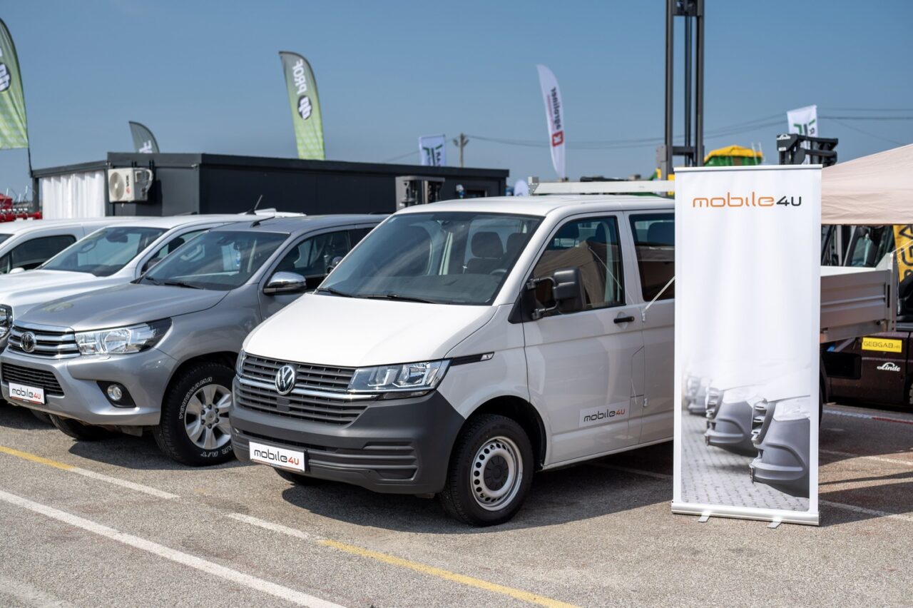 Automobili i kombi parkirani pored roll-upa na sajmu